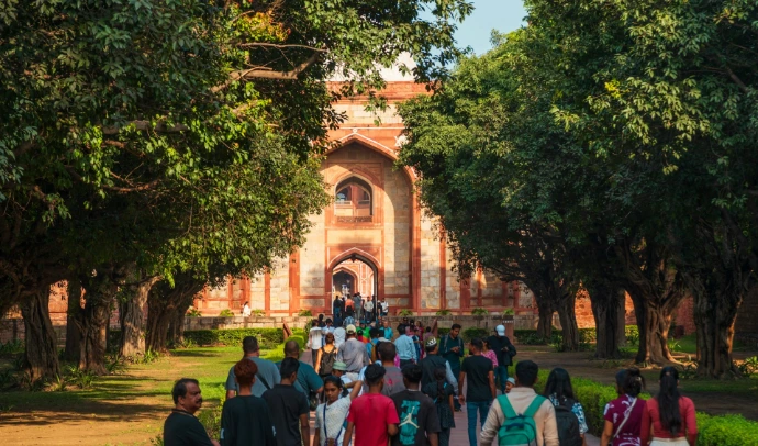People walking towards an ancient arched building entrance